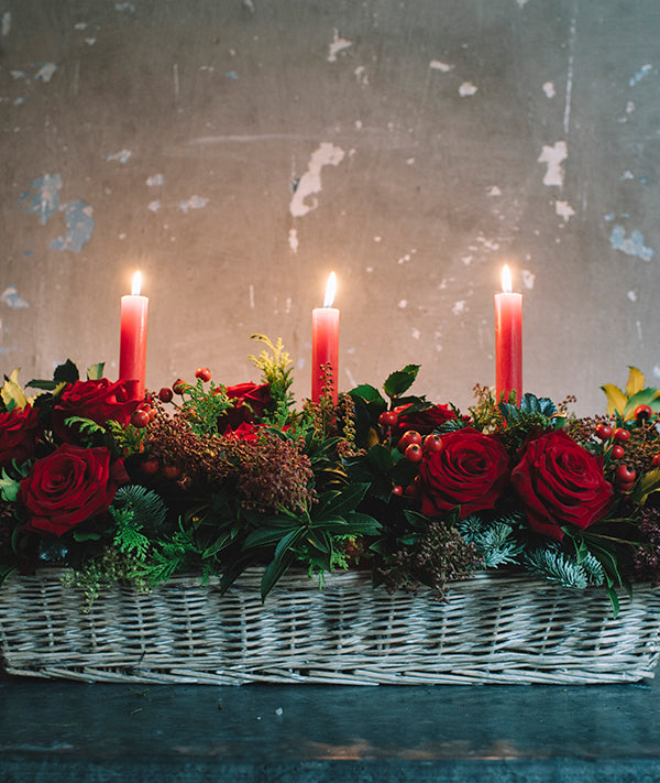 Centro de mesa con verdes y flores navideñas y velas
