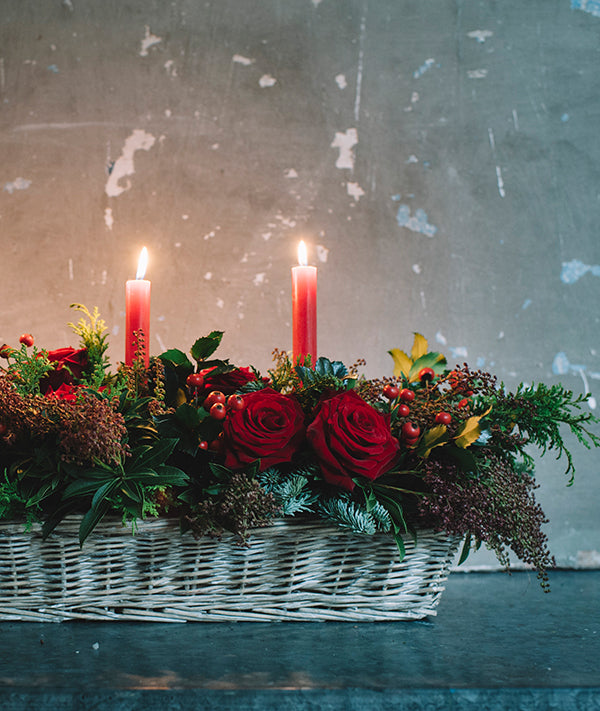 Centro de mesa con verdes y flores navideñas y velas